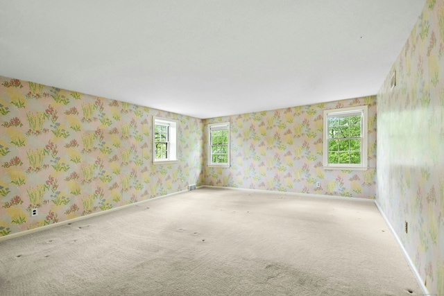 unfurnished room featuring wallpapered walls, carpet floors, and baseboards