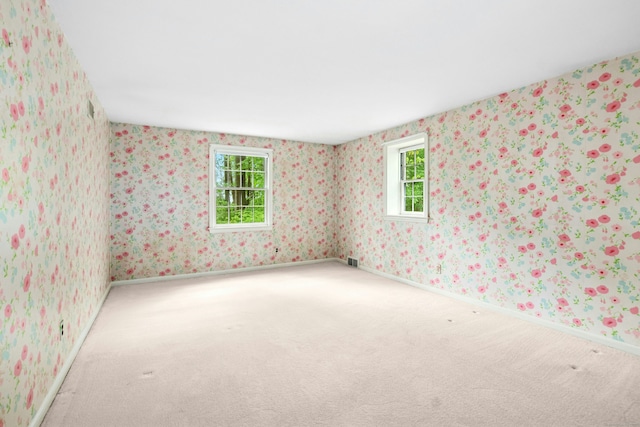 empty room featuring carpet floors, wallpapered walls, and baseboards