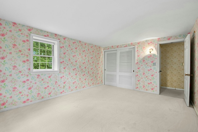 unfurnished bedroom featuring light carpet, a closet, and baseboards