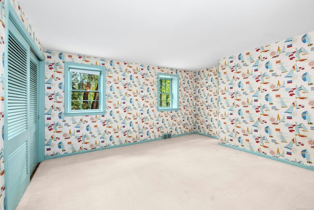 carpeted spare room with wallpapered walls and healthy amount of natural light