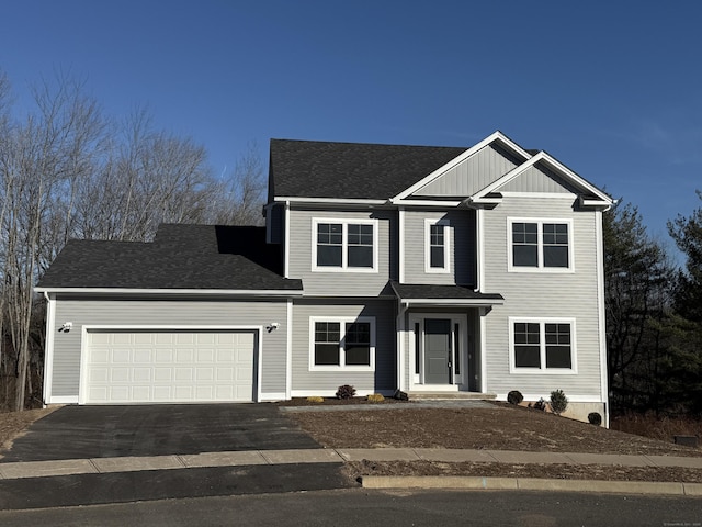 view of front facade with driveway, a garage, and a shingled roof