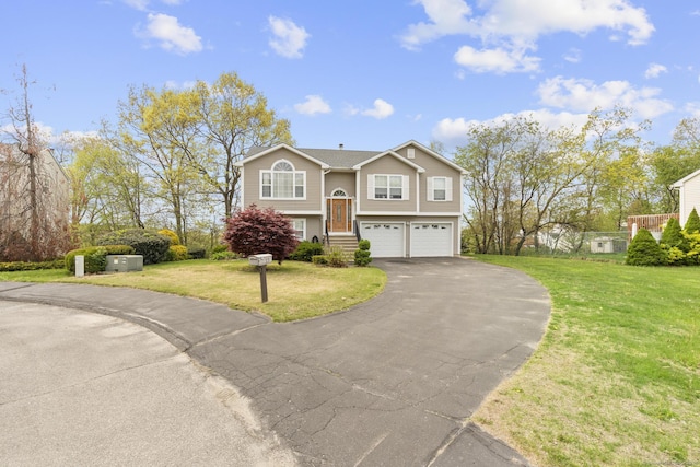 split foyer home with an attached garage, a front yard, and aphalt driveway