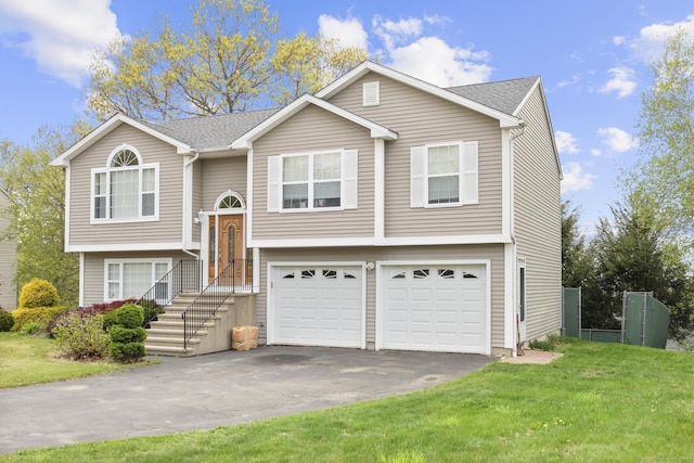split foyer home with an attached garage, a front lawn, a shingled roof, and driveway