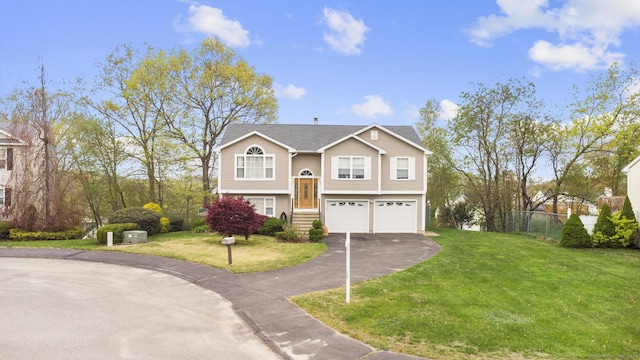 bi-level home featuring fence, an attached garage, a front lawn, and driveway
