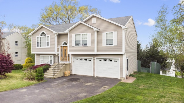 raised ranch with aphalt driveway, a garage, and a front yard