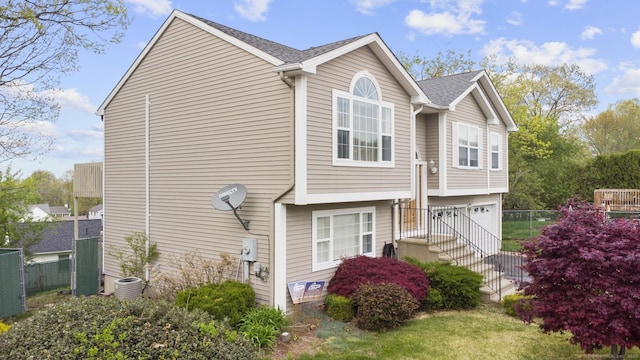 view of property exterior with fence, an attached garage, and central AC