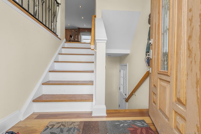 stairs with wood finished floors, baseboards, and recessed lighting