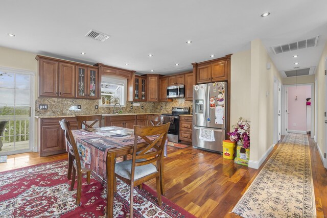 kitchen featuring appliances with stainless steel finishes, wood finished floors, tasteful backsplash, and recessed lighting
