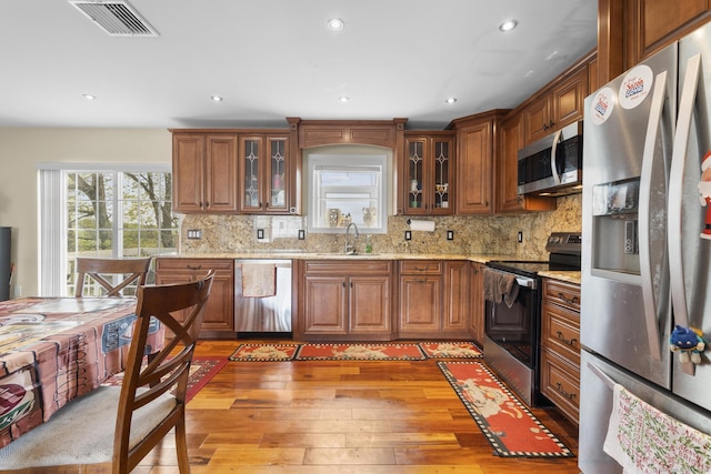kitchen featuring light wood-style flooring, a sink, visible vents, appliances with stainless steel finishes, and decorative backsplash