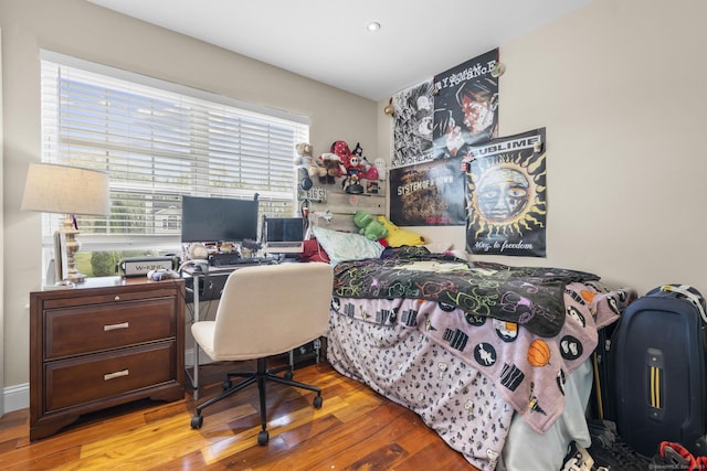 bedroom featuring wood finished floors and an office area