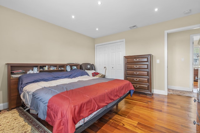 bedroom featuring wood finished floors, a closet, visible vents, baseboards, and recessed lighting