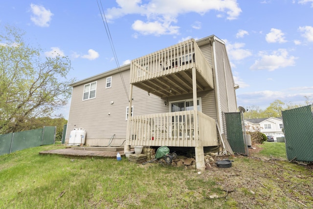 rear view of property featuring a yard, a wooden deck, fence, and a balcony