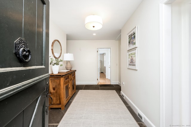 corridor featuring dark tile patterned floors and baseboards