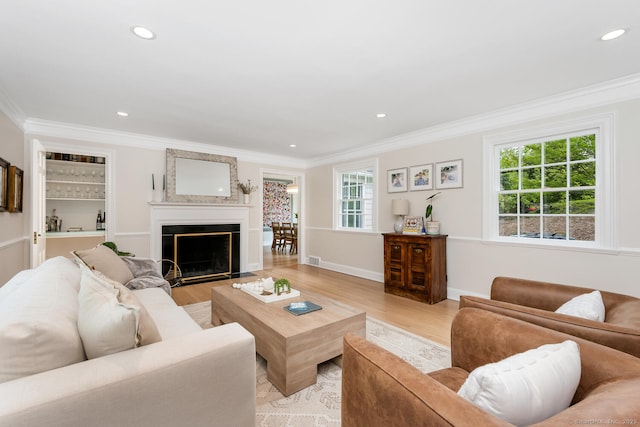 living area featuring crown molding, recessed lighting, light wood finished floors, a fireplace, and baseboards