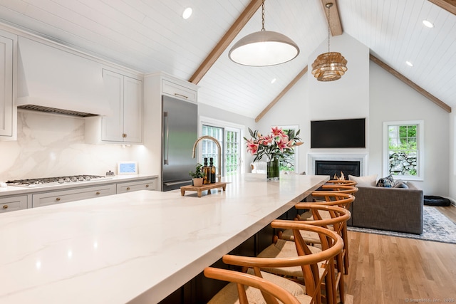 kitchen with gas cooktop, built in refrigerator, white cabinets, beam ceiling, and light wood-style floors
