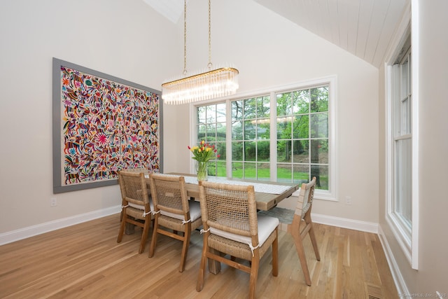 dining area featuring lofted ceiling, a chandelier, light wood-style floors, and baseboards