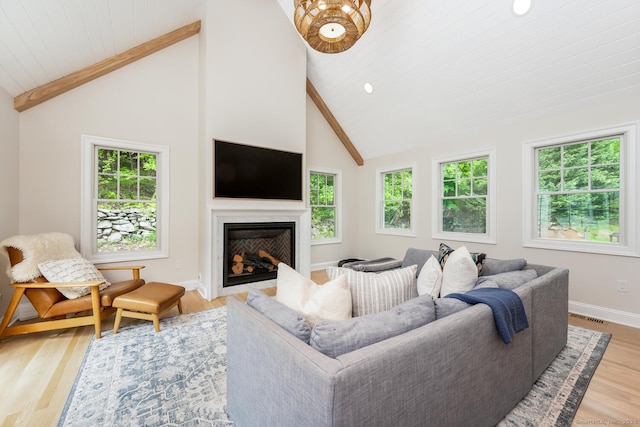 living area with plenty of natural light, beamed ceiling, light wood-style flooring, baseboards, and high vaulted ceiling