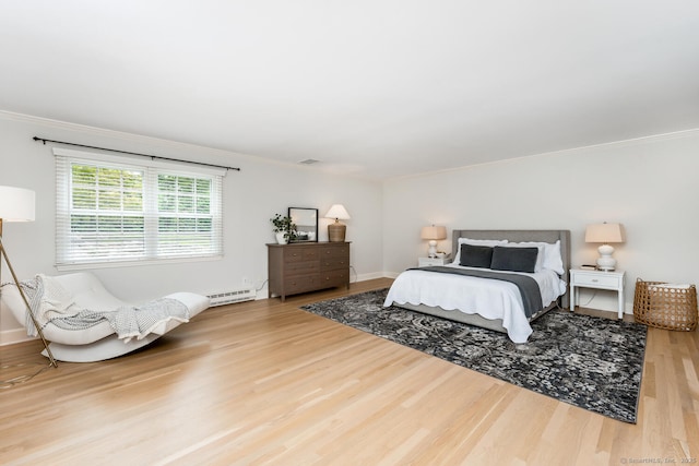 bedroom with wood finished floors, ornamental molding, a baseboard radiator, and baseboards