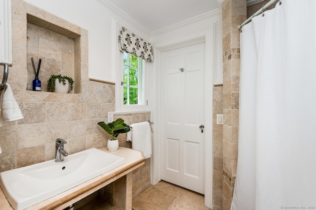 bathroom with tile walls, ornamental molding, a sink, and a tile shower