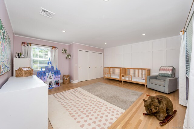 bedroom featuring wood finished floors, a closet, a decorative wall, and recessed lighting