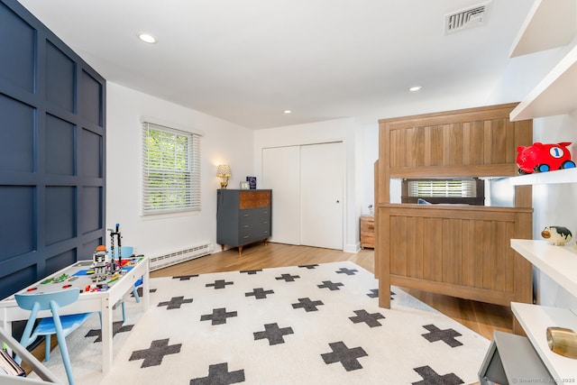 bedroom featuring a baseboard radiator, wood finished floors, a closet, and recessed lighting
