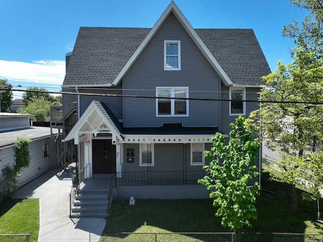 view of front of home with a porch, a front lawn, and a shingled roof