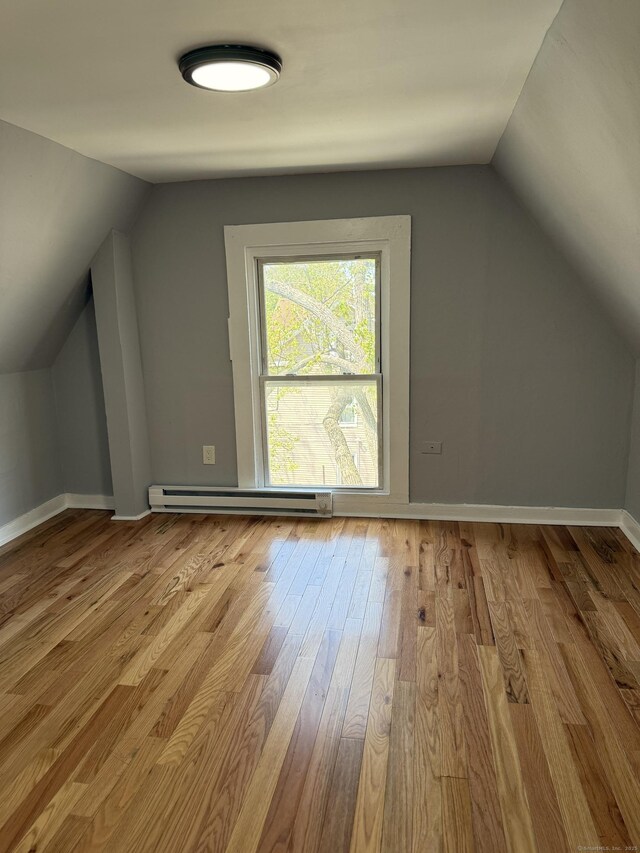 bonus room with a baseboard heating unit, vaulted ceiling, hardwood / wood-style floors, and baseboards
