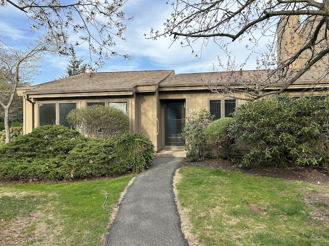 single story home featuring a shingled roof and a front yard