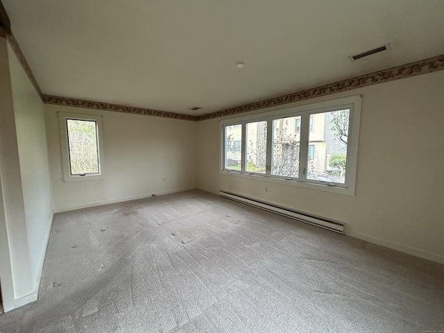 empty room with light colored carpet, visible vents, baseboards, and a baseboard heating unit