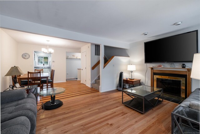201 Greens Farm Rd Unit 201, Branford, CT 06405 - living room with stairs, light wood-style floors, a chandelier, a fireplace, and baseboards