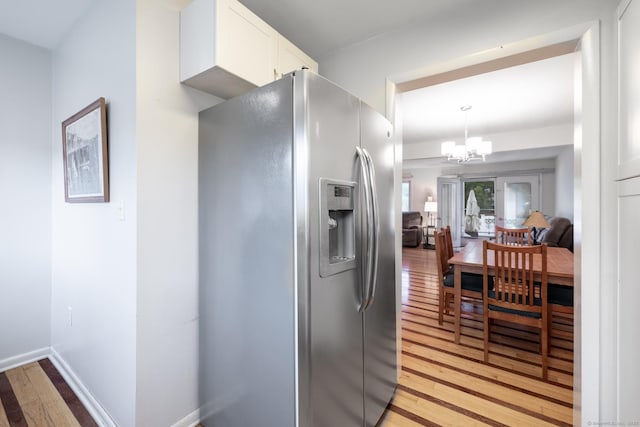 201 Greens Farm Rd Unit 201, Branford, CT 06405 - kitchen with stainless steel refrigerator with ice dispenser, light wood finished floors, a chandelier, and white cabinets