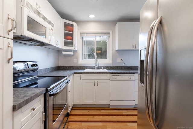 201 Greens Farm Rd Unit 201, Branford, CT 06405 - kitchen featuring stainless steel appliances, a sink, white cabinets, light wood-type flooring, and dark countertops