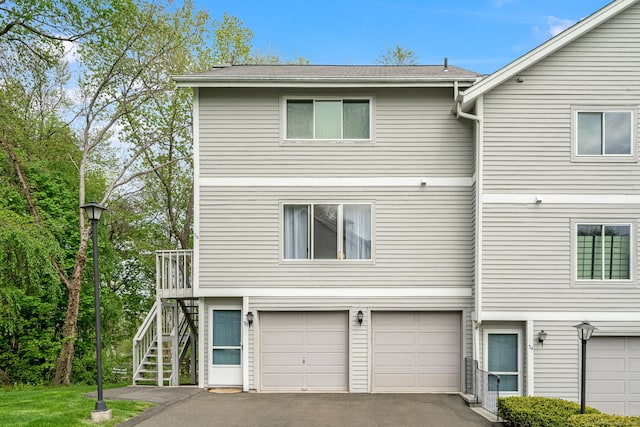 view of front of house featuring stairway, a garage, and aphalt driveway