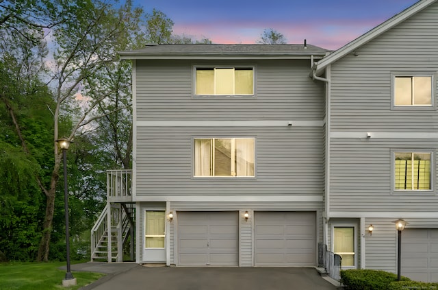view of front facade with stairs, an attached garage, and driveway