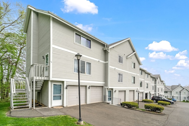 exterior space featuring driveway, stairway, a residential view, and an attached garage