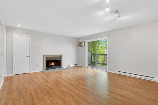 unfurnished living room with a baseboard radiator, a wall mounted air conditioner, a glass covered fireplace, and light wood-type flooring