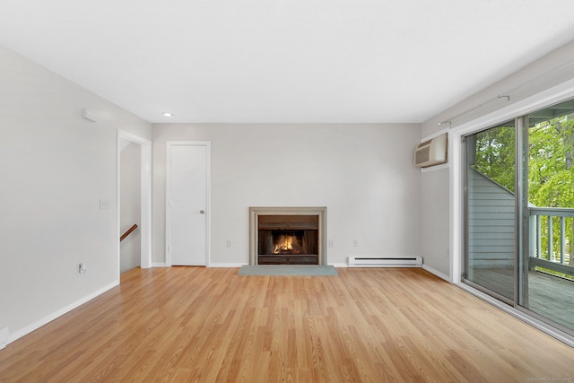 unfurnished living room featuring a baseboard radiator, a wall mounted AC, baseboards, a lit fireplace, and light wood-type flooring