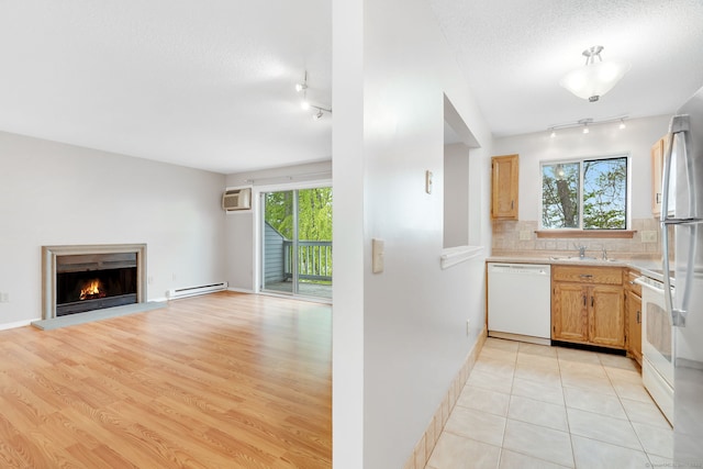 kitchen with rail lighting, white appliances, a baseboard radiator, and a sink