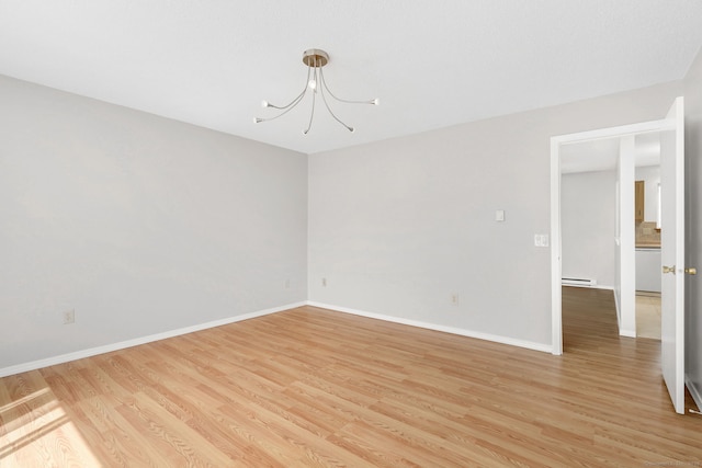 empty room with a chandelier, light wood-style flooring, baseboards, and a baseboard heating unit