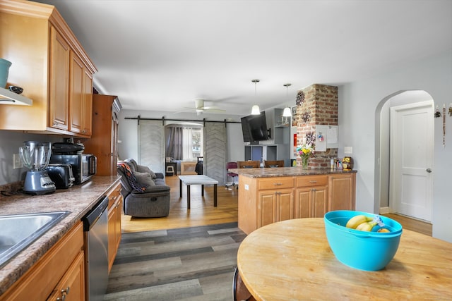 kitchen with stainless steel appliances, open floor plan, dark wood finished floors, a barn door, and arched walkways