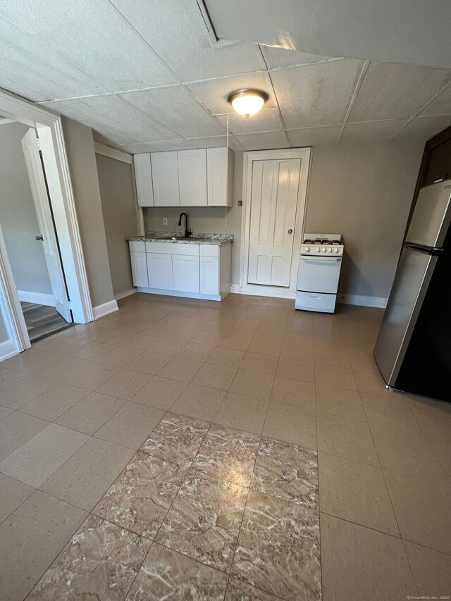 252-254 Liberty St, Meriden, CT 06450 - kitchen with freestanding refrigerator, white range with gas cooktop, baseboards, white cabinetry, and a drop ceiling