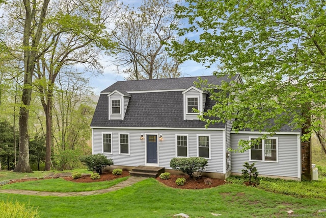 colonial inspired home with roof with shingles and a front lawn