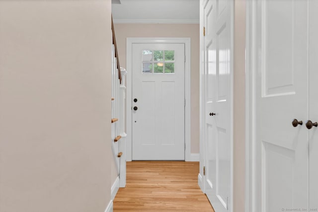 doorway with light wood finished floors, crown molding, and baseboards