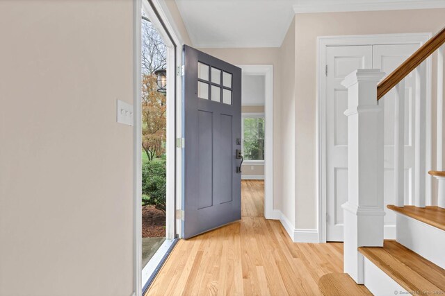 foyer entrance featuring wood finished floors, ornamental molding, baseboards, and stairs