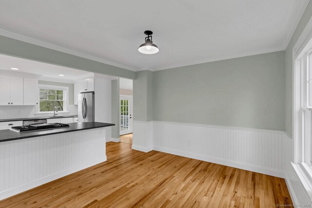 kitchen featuring freestanding refrigerator, light wood-style flooring, dark countertops, white cabinets, and healthy amount of natural light