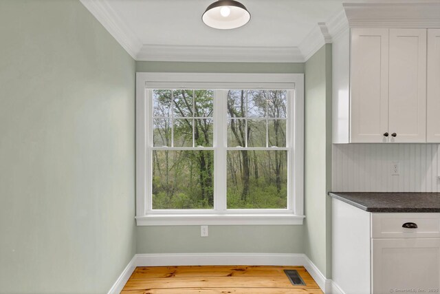 unfurnished dining area with crown molding, baseboards, and light wood finished floors