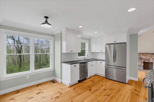 kitchen featuring appliances with stainless steel finishes, a sink, white cabinets, dark countertops, and baseboards