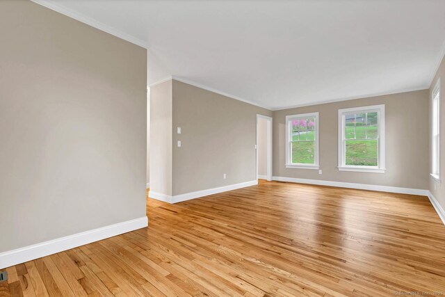 spare room featuring baseboards, crown molding, and light wood-type flooring