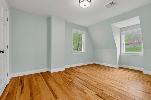 additional living space featuring healthy amount of natural light, light wood-style flooring, and baseboards