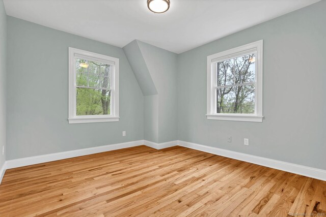 additional living space with baseboards and light wood-type flooring